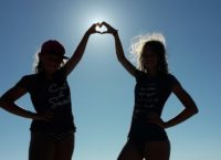 Zwei Mädchen die mit Ihren Händen der Sonne entgegen ein Herz formen.