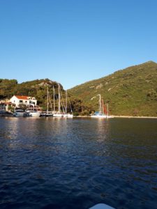 Man sieht eine Marina am Ufer einer kroatischen Insel, vor Ihr haben einige Segelboote und auch ein paar Motorboote angelegt.