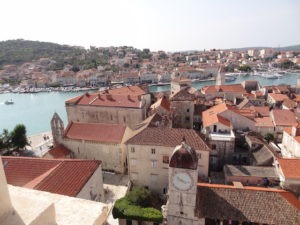 Blick über die Stadt. Man sieht von hier oben aus die kleinen verwinkelten Gassen der kroatischen Stadt die kupferroten Dächer und auch der Hafen ist im Hintergrund zu erkennen.