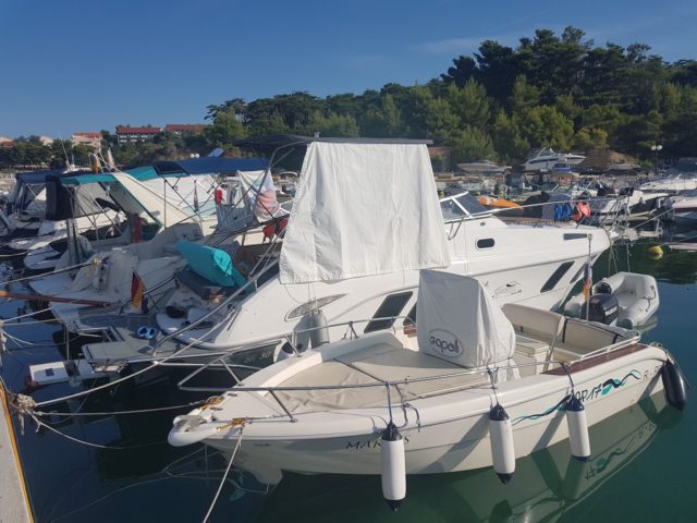 Man sieht die SR30 Yachtline mit vielen anderen Booten im Hafen liegen auf der rechten seit ist ein Sonnensegel befestigt der jüngste Sohn der Familie liegt auf dem Boot im Schatten.