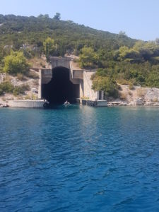 The turquoise blue water of the Mediterranean and the well-known submarine bunkers in the background, which have been built into the mountain.